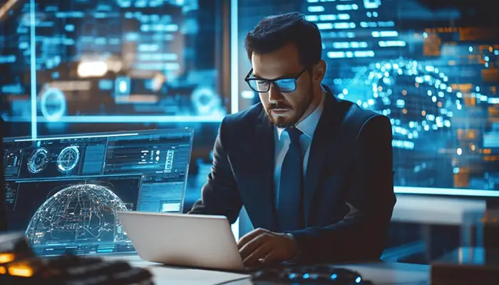 Professional man in a suit and glasses working on a laptop in a high-tech control room with holographic displays behind him